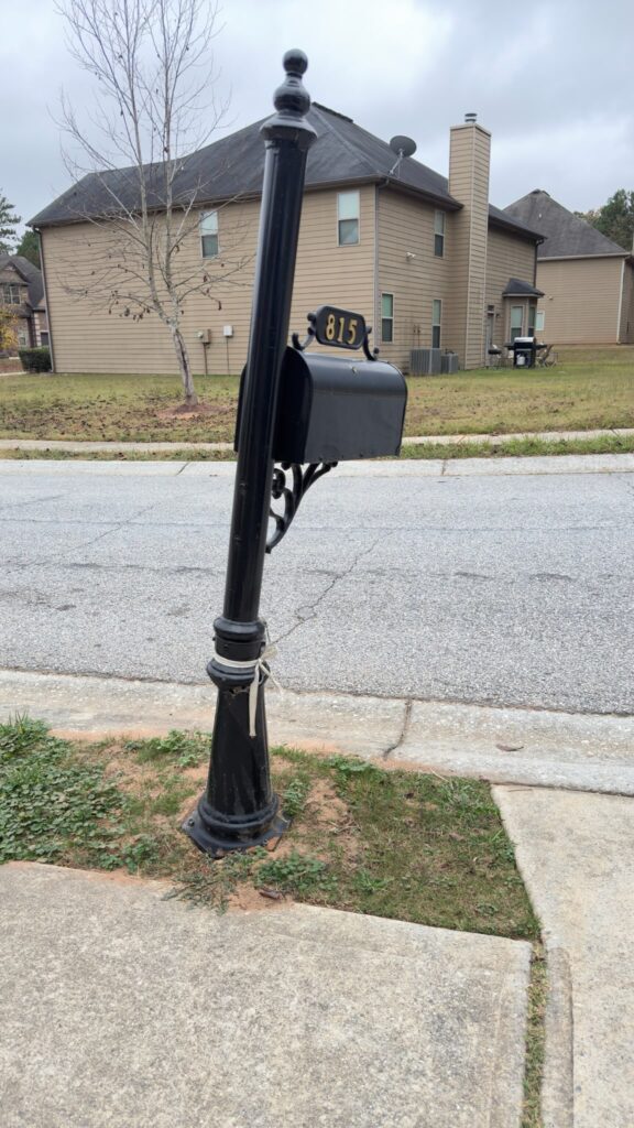 Leaning and damaged mailbox post in a residential neighborhood.